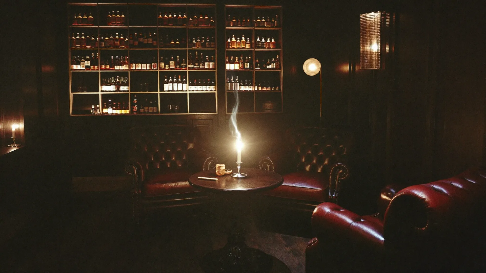 Backlit shelves of single malt whisky bottles glowing amber behind a dark walnut bar